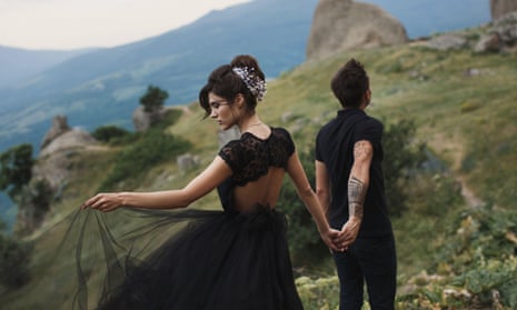 A woman in a black gown with a man in black clothes in a hill top location