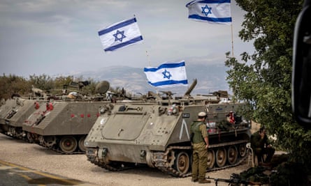 Three armoured military vehicles flying Israeli flags parked in a line