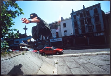 A person skating up a ramp, with derelict buildings in the background