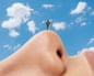 A person stands on a giant nose under a sky with clouds