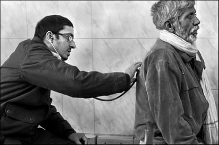A doctor listens to a man’s chest with a stethoscope 