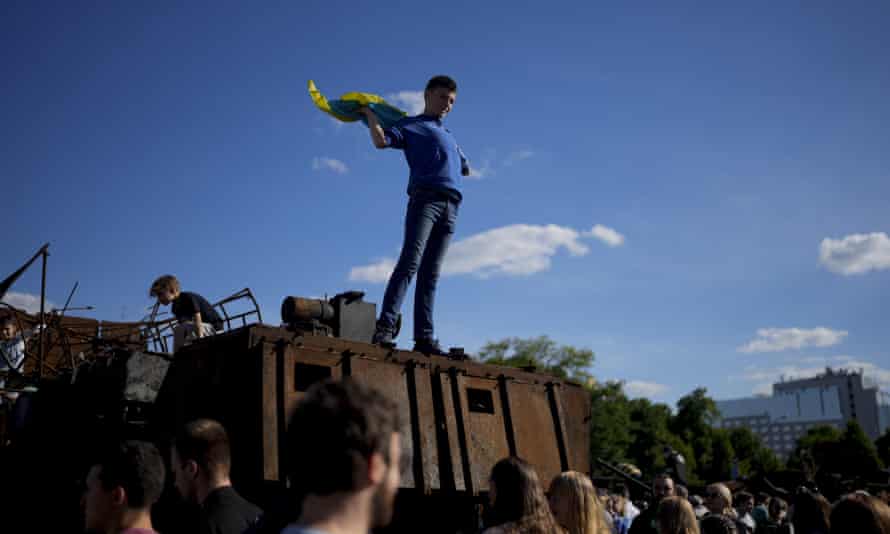 A boy holds a Ukrainian flag on a destroyed Russian tank placed as a symbol of war during Kyiv Day celebrations in downtown Kyiv, Ukraine.