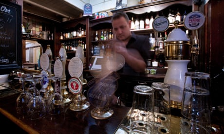 A barman pouring a draught beer behind a bar