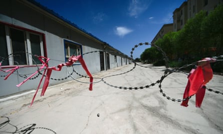 Barbed wire with red ribbons attached in front of a facility