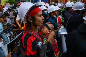 A protester carries a child during a demonstration against the 1 February military coup in Yangon.
