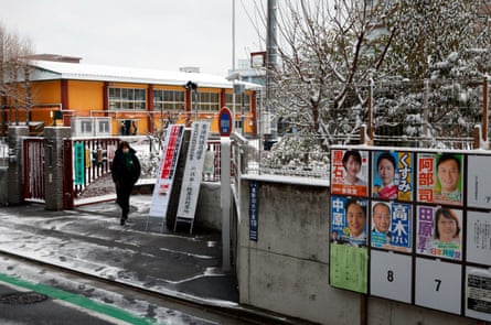 A voter exits a polling station after voting in a snowy Tokyo