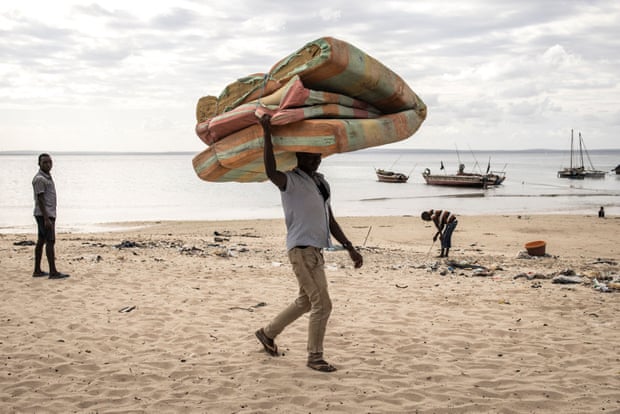 A man carries a mattress as he arrives at Paquitequete beach in Pemba, after fleeing Palma by boat with 49 other people.