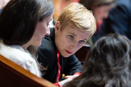 Closeup of Clémentine Autain leans over talking to female colleagues in parliament