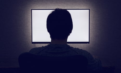 Man sits in front of a blank monitor in dark room