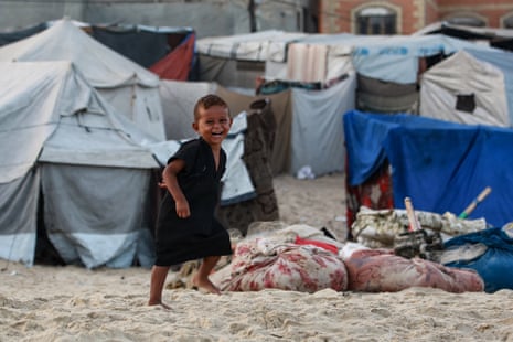 A displaced Palestinian child runs amid tents in Deir el-Balah in the central Gaza Strip.