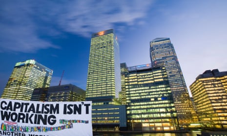 Banking and financial sector buildings at Canary Wharf, behind a poster that says 'Capitalism isn't working.'