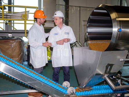 Two people in industrial food production clothes and helmets.