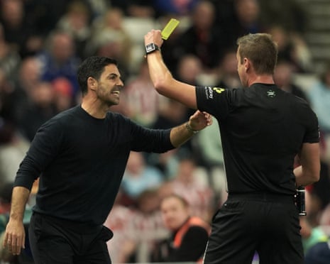 Referee John Brooks shows a yellow card to the Arsenal manager Mikel Arteta during the Premier League match against Sunderland.