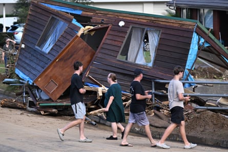 Residents walk past part of a home washed up onto Koloona Avenue in Mt Kiera, Wollongong, on Sunday.
