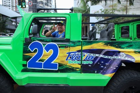 A Flavio Bolsonaro supporter rides in a bright green truck decorated with campaign stickers for the far-right presidential candidate