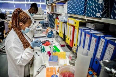 Two young African women putting samples into trial tubes successful a laboratory