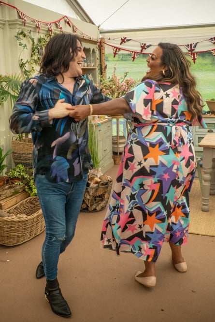 Noel Fielding in jeans and a long-sleeved shirt dancing in a tent with Alison Hammond, in a long dress
