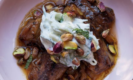 A mound of slow-cooked spiced aubergine with cucumber yogurt heaped on top, piled with pistachios