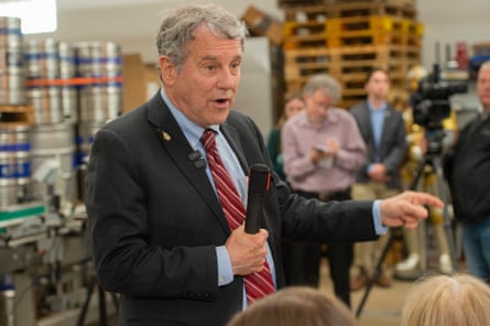 A man in suit and tie speaks to a crowd of people.