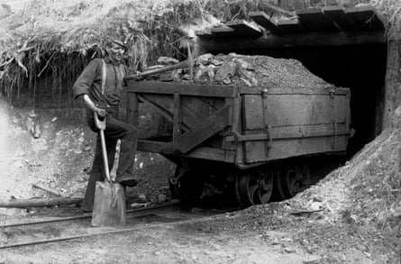 Miner standing at a drift mouth with a coal cart he loaded by hand
