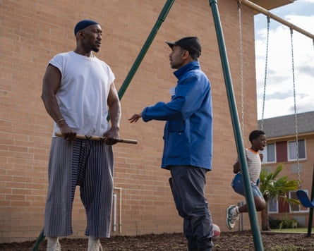 Two men talking and boy on swing set