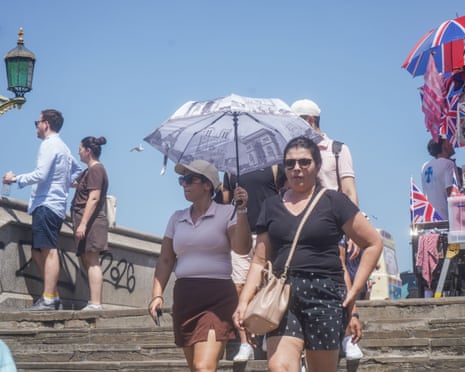 Pedestrians on Westminster Bridge brave the sweltering conditions in London, UK.