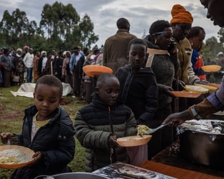 Children receive spoonfuls of food on their plates