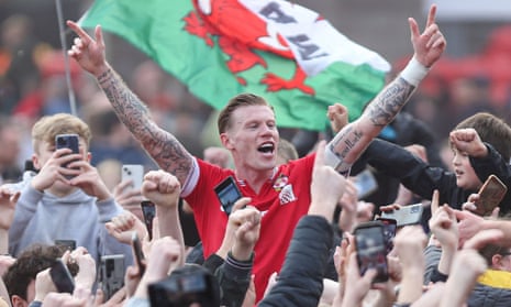 James McClean celebrates with fans on the pitch after Wrexham sealed promotion to League One on 13 April 2024.