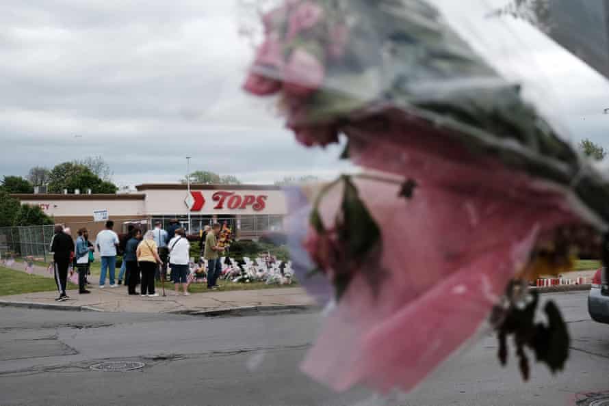 People gather at a memorial for the shooting victims outside of Tops grocery store.