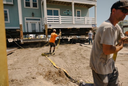 A crew holding chains and tow straps secures a home to prep