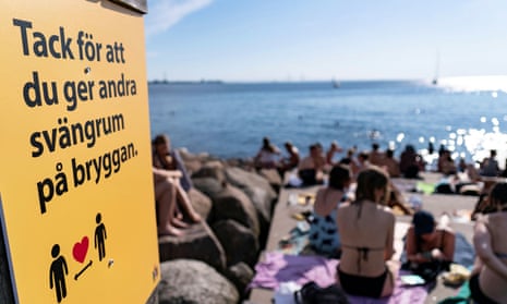 An information sign recommends people to keep social distance due to Covid-19 pandemic, where people sunbathe and swim at a bathing jetty in Malmo, Sweden.
