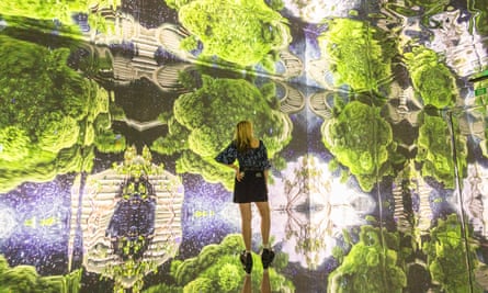 woman standing in front of large kaleidoscopic imagery of greenery
