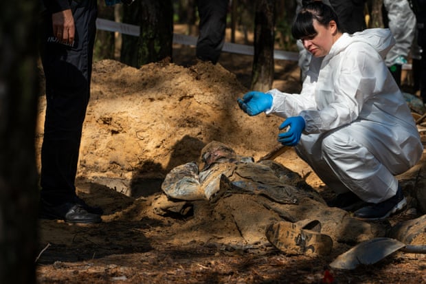 An emergency services member examines an unearthed body at the extension of a cemetery near Izium on 17 September.