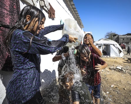 a group of kids with a jug of water pouring it over each other to cool off