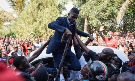 Bobi Wine is helped down from the top of a car on Thursday after he addressed a crowd outside his home in Kampala.