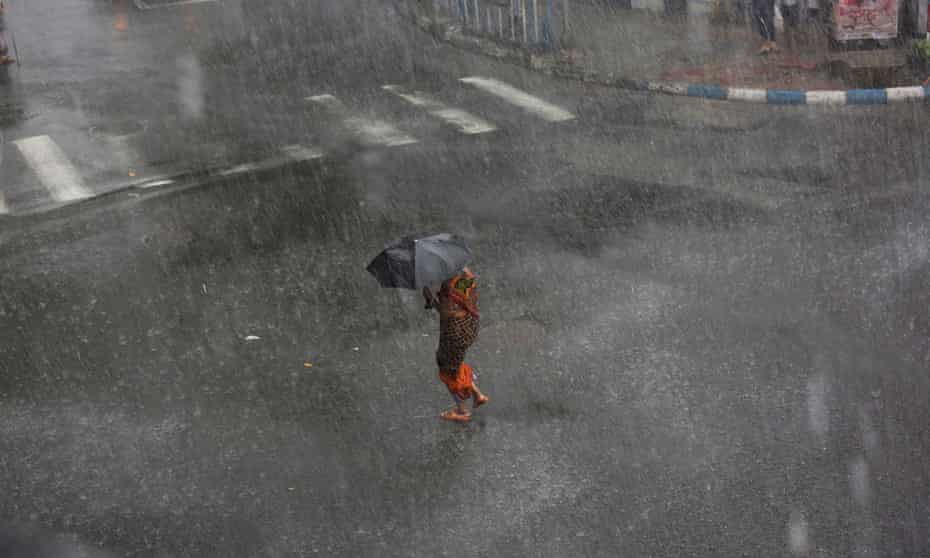 A woman tries to manage her umbrella between storm with heavy rain on street in Calcutta, eastern India, 23 May 2016.