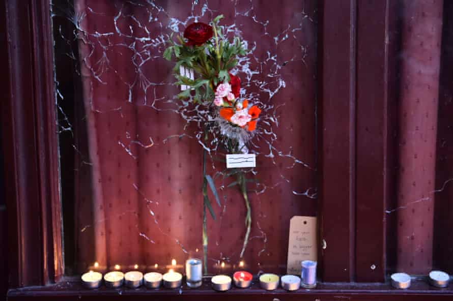 Candles have been lit next to a flower” hanging on a broken window of “Le carillon” restaurant one of the site of the attacks in Paris on November 15, 2015