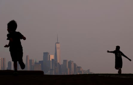 Two young children running, a cityscape in the background