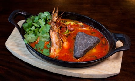 A sizzling good time: blanched prawns in a cast-iron skillet with tomato, harissa, salty lemon sauce—and a hot stone.