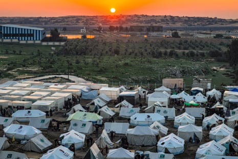 The sun sets in Egypt across the border from the southern Gaza Strip. Tents housing Palestinians displaced by the conflict can be seen in Rafah in the southern Gaza Strip