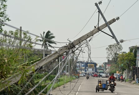 People ride a motorcycle past a toppled electrical post caused by Typhoon Yinxing, locally called Marce, in Camalaniugan