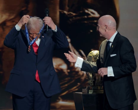 Gianni Infantino looks on as Trump places the medal around his neck.