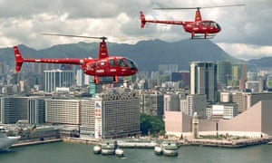 Two red helicopters fly over Hong Kong