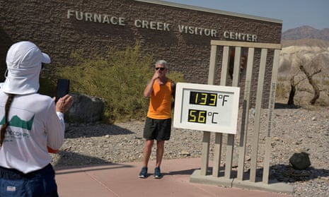 A person poses for a photo next to a thermometer readout in Death Valley, California