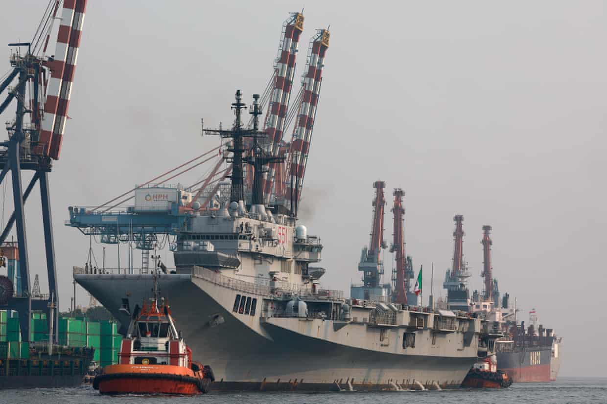 Small boat near aircraft carrier at a dock