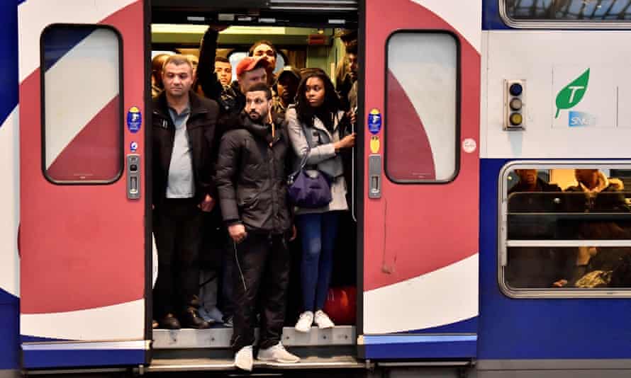 Commuters stand in the doorway of a crowded train in Paris.