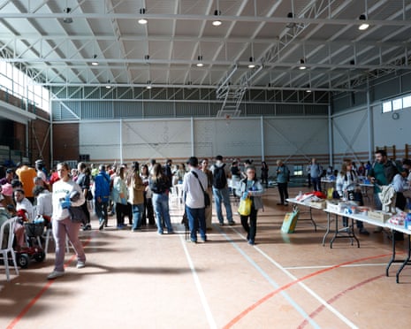 Train accident survivors gather in a makeshift gymnasium camp with tables of supplies