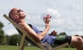 Phil Daoust, holding an ice-cream cone, reclines in a deckchair in the park in the sunshine
