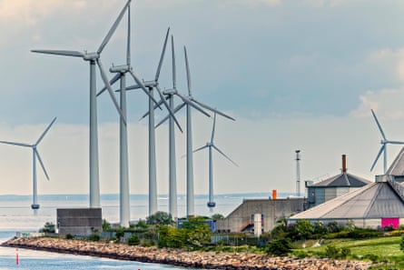 Wind turbines in the water next to a house by the coast