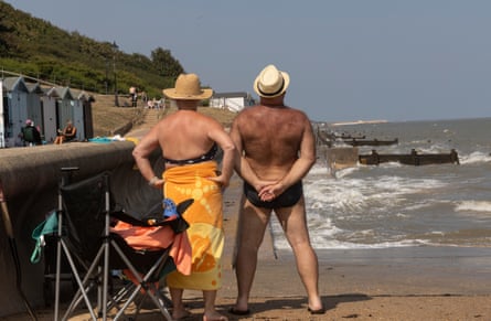 A man and women in swimming atire stand by the water